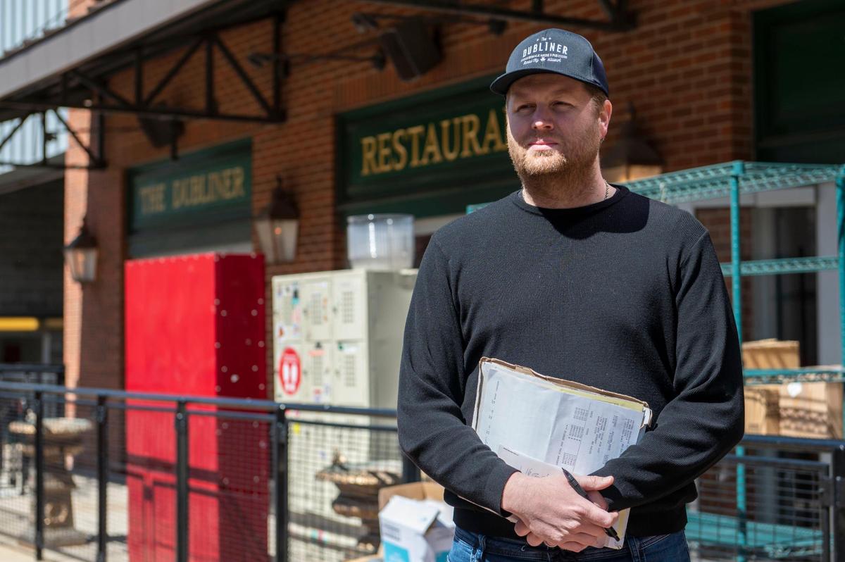 Ryan Haverty, a co-owner of The Dubliner, holds a folder filled with invoices as he watches movers haul away furniture and moving boxes from the Irish pub at Power & Light District on Friday, April 1, 2022.