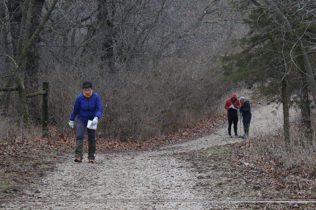 During a Possum Trot Orienteering Club event, Lawrence resident Lisa Grossman makes her way up a hill at the Prairie Center preserve in Olathe while Overland Park residents Michael Semidubersky and Mike Shifman consult their map.