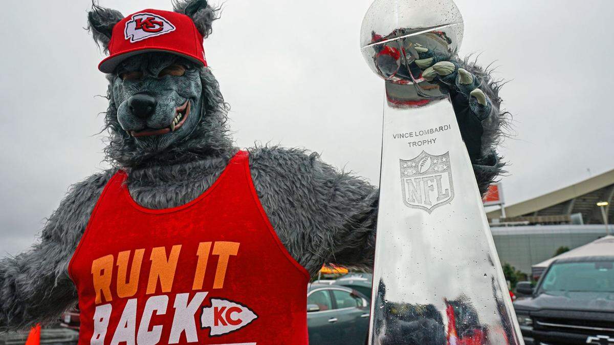 A Kansas City Chiefs fan dressed as a wolf poses for a photo with a replica of the Vince Lombardi Trophy before the game against the Houston Texans at Arrowhead Stadium.