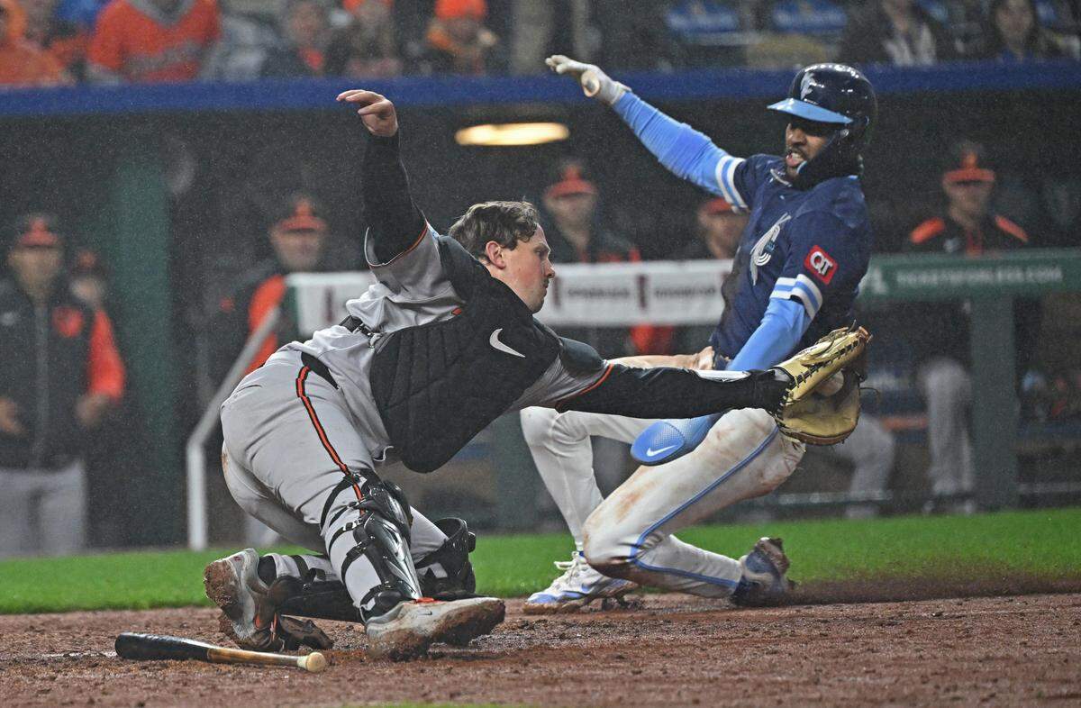 Kansas City Royals third baseman Maikel Garcia (11) slides home to score a run against Baltimore Orioles catcher Adley Rutschman (35) in the eighth inning at Kauffman Stadium on Apr 4, 2025 in Kansas City, Missouri, USA.