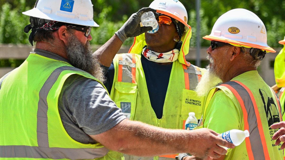 A Kansas City Streetcar construction crew took a break from the intense heat last week. Bruce Eversole, from left, hands out water to crew members as Tim Reed takes a drink during a water break. The crew was working on the streetcar extension project near Main Street near Pershing Road.