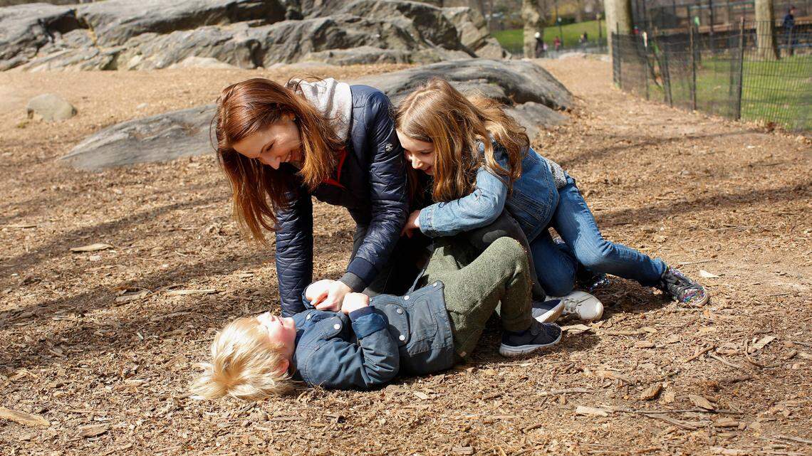 Kids playing with their mom outside.