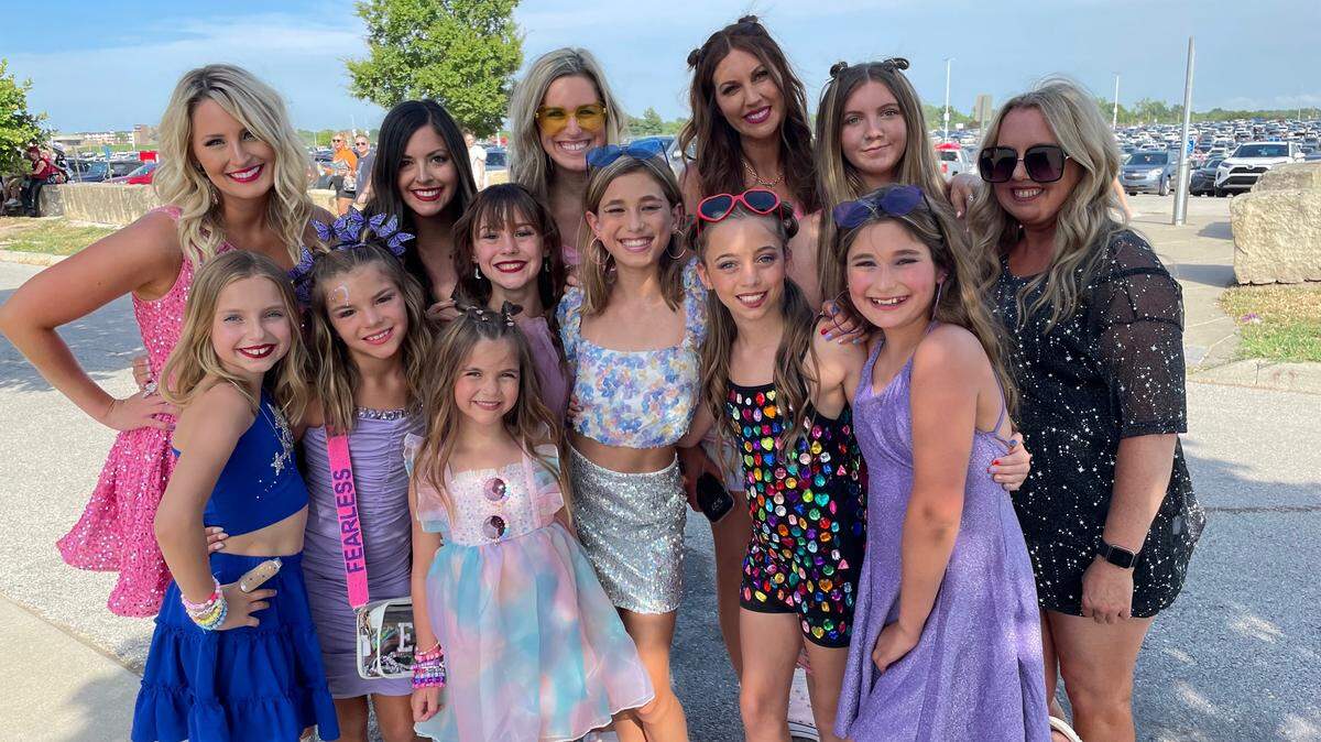 Hattie Nielsen, a 6-year-old from St. Louis, attends the Taylor Swift Eras Tour concert at Arrowhead Stadium in Kansas City. She stands in the front, third over from the left with the sunglasses in her dress.