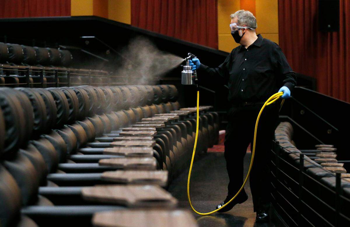In Dallas, Cinemark West general manager Lindsey Hearn sprays disinfectant on seats in an auditorium the morning before the theater’s June 19 reopening.