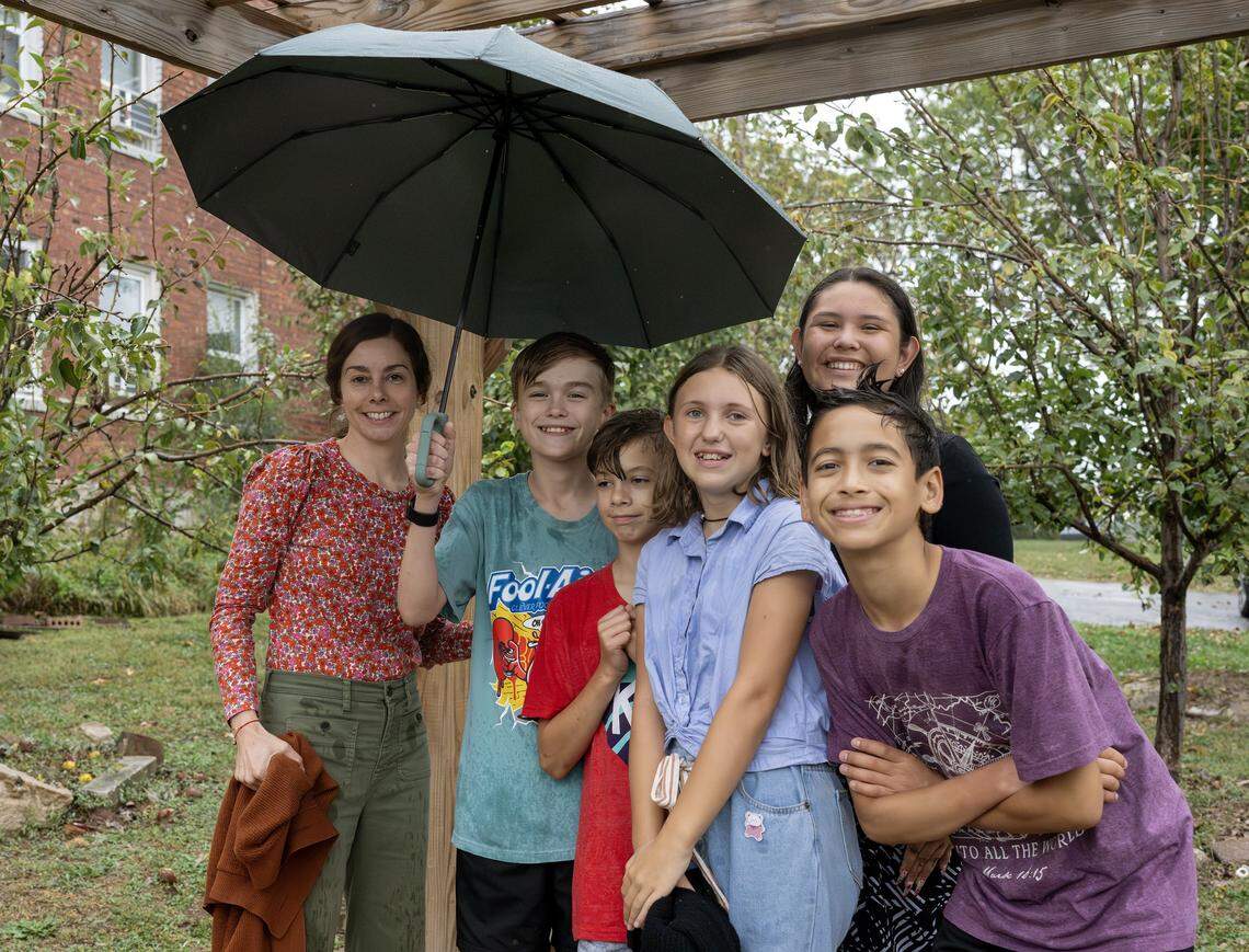 Pendleton Heights Community School teacher Jen Lacy stands under an umbrella with her students at the community orchard on Tuesday, Oct. 14, 2025, in Kansas City. Lacy and her students are advocating to preserve the orchard, which could be replaced by a parking lot.