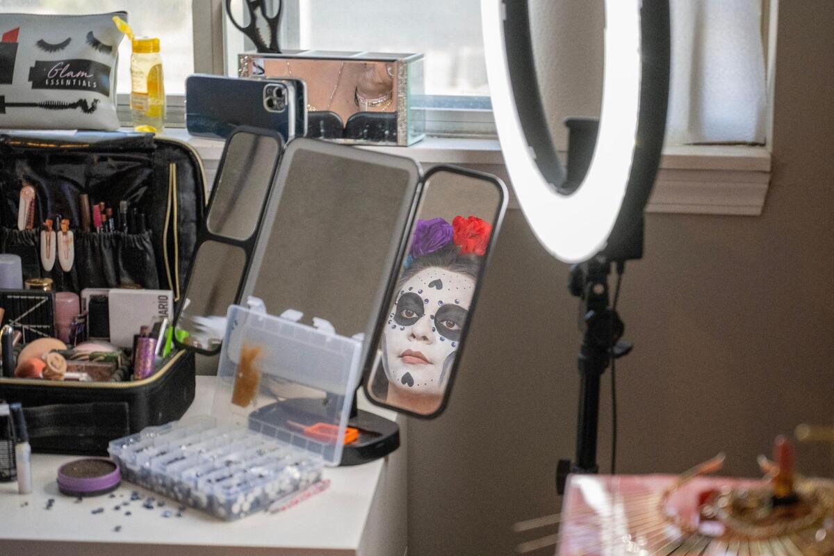 Yulissa Lopez looks in the mirror after her face is painted like a Catrina by Daniella Briones.