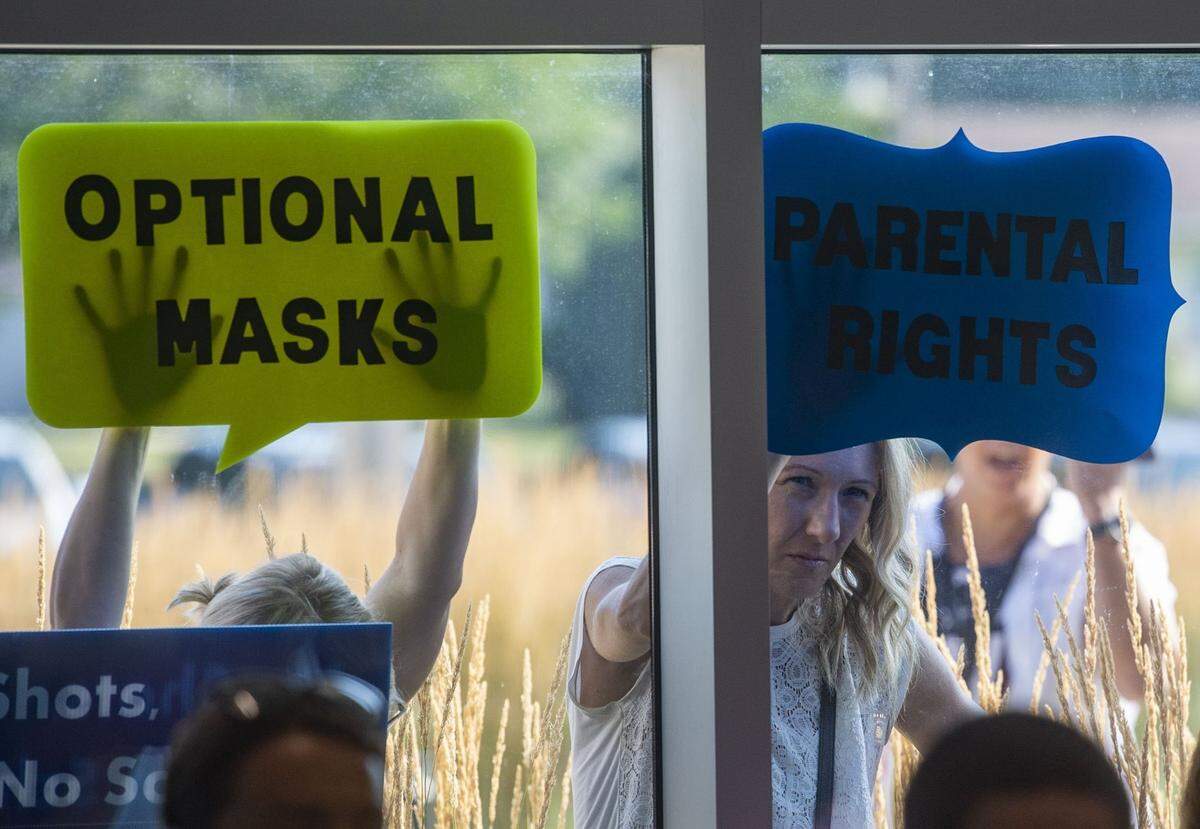People stand with signs outside a July 2021 Shawnee Mission School District meeting during discussions about mask requirements in the 2021-22 school year. The issue has continued to bring controversy to school districts across the Kansas City area.