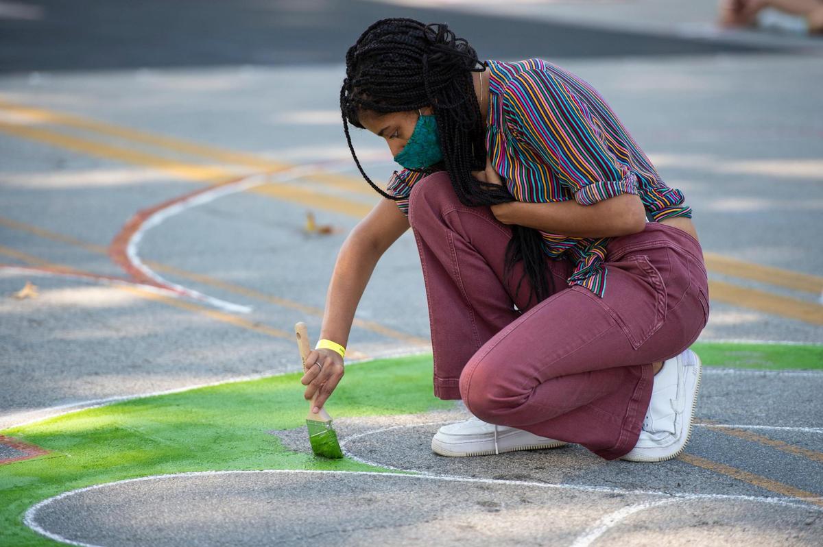 Bella Barnes worked with bright green paint to start filling in a giant “B” on the Black Lives Matter mural being painted on Brookside Blvd. Saturday near 63rd St.