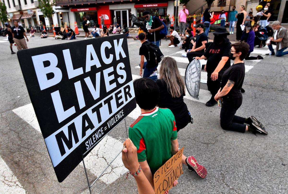 During a George Floyd Memorial March held Tuesday night on the Country Club Plaza, protesters kneel at an intersection for a moment of silence in memory of Floyd, who was killed one year ago by a police officer in Minneapolis, Minnesota. The event was organized by Black Rainbow of Kansas City.