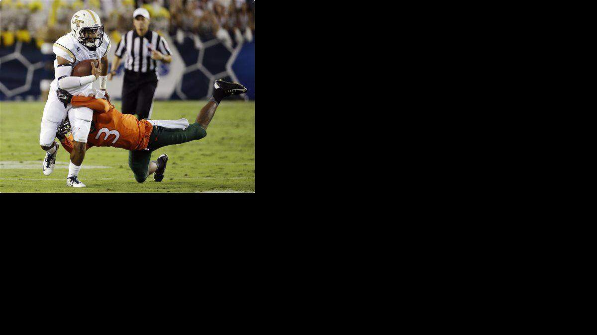 Georgia Tech quarterback Justin Thomas, left, is tackled by Miami's Tracy Howard