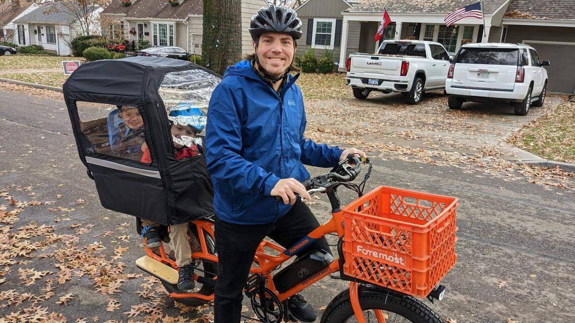 Zach Flanders rides his cargo e-bike with his two young children on Sunday, Nov. 27, 2022. Flanders ferries his children to and from elementary school and preschool on the bike most days, although colder weather and adverse road conditions can stand in the way.