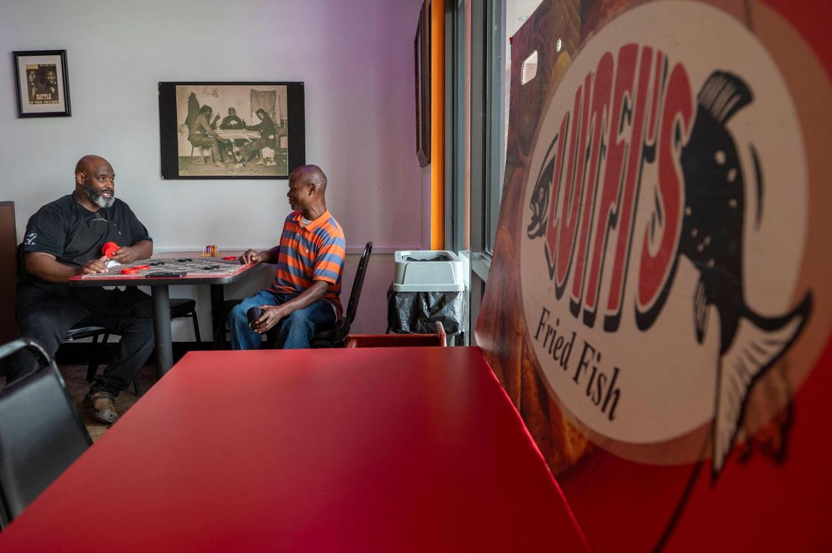 Lutfi Khalifa, left, and his cousin Byron Hill play checkers as they wait for customers to arrive at his Lutfi’s Fried Fish restaurant in Lee’s Summit.