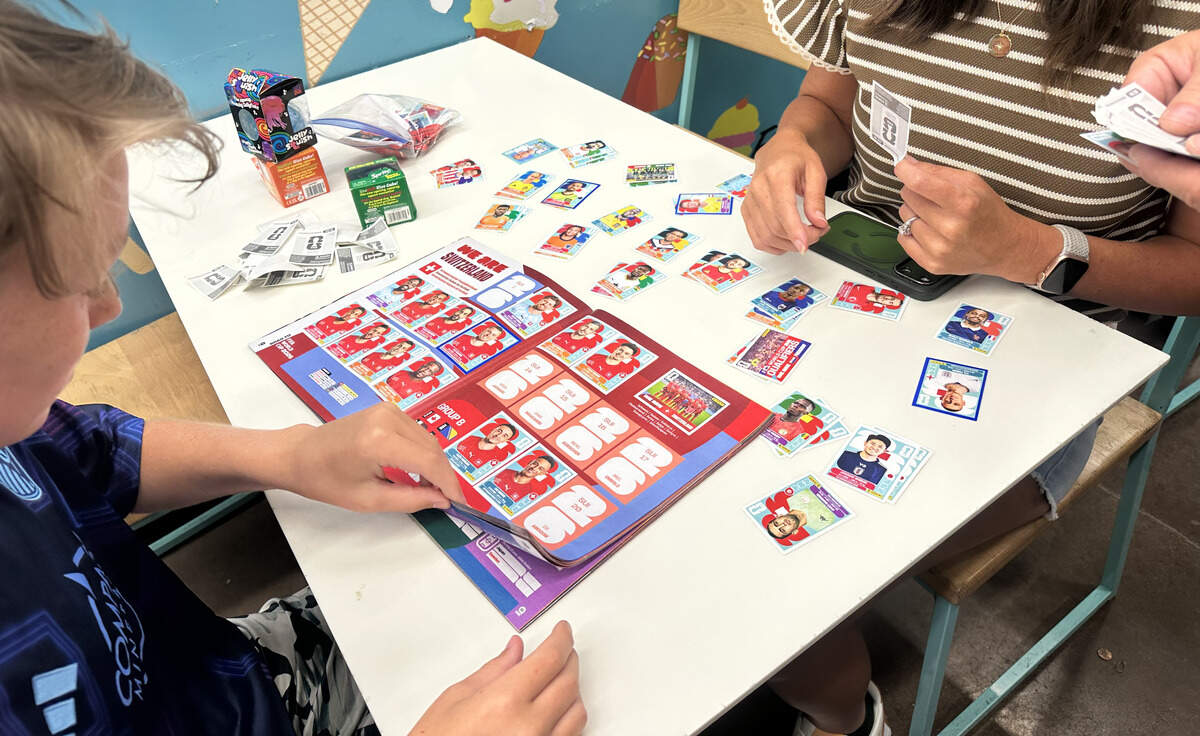 Easton Kling organizes his Panini stickers on his album while his mom, Erin, and his dad, Justin, pass him cards. The family got a free album a few weeks ago, and found the World Fresh Market event online to fill it out.