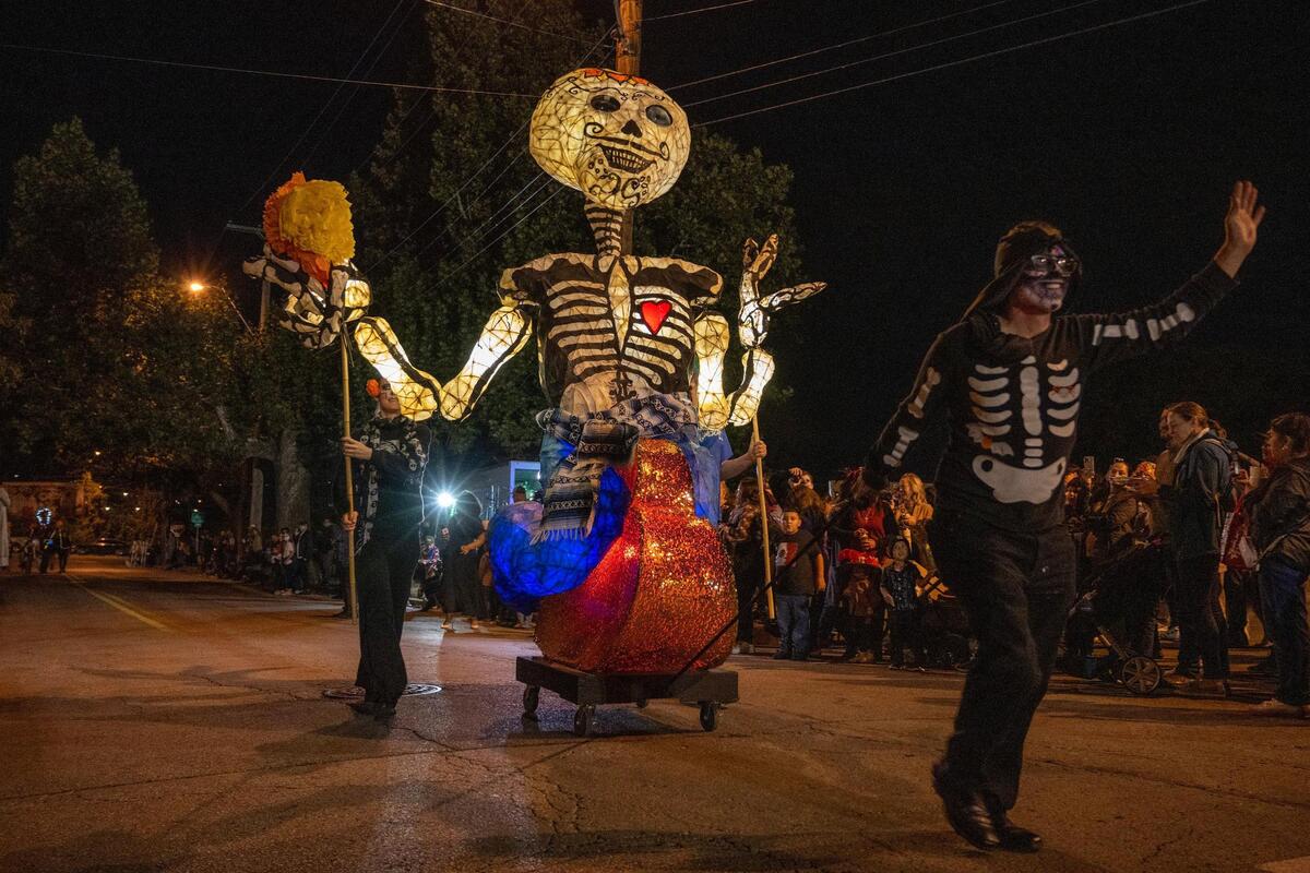 Parade participants walk along West 17th Street during the Dia de los Muertos festival parade at the Mattie Rhodes Center.