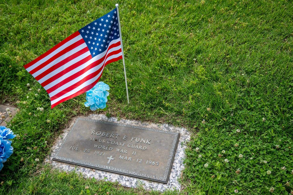 A U.S. flag is seen above the grave stone of Robert E. Funk, a U.S. Coast Guard World War II veteran, at Forest Hill Calvary Cemetery on Friday, May 24, 2024, in Kansas City.