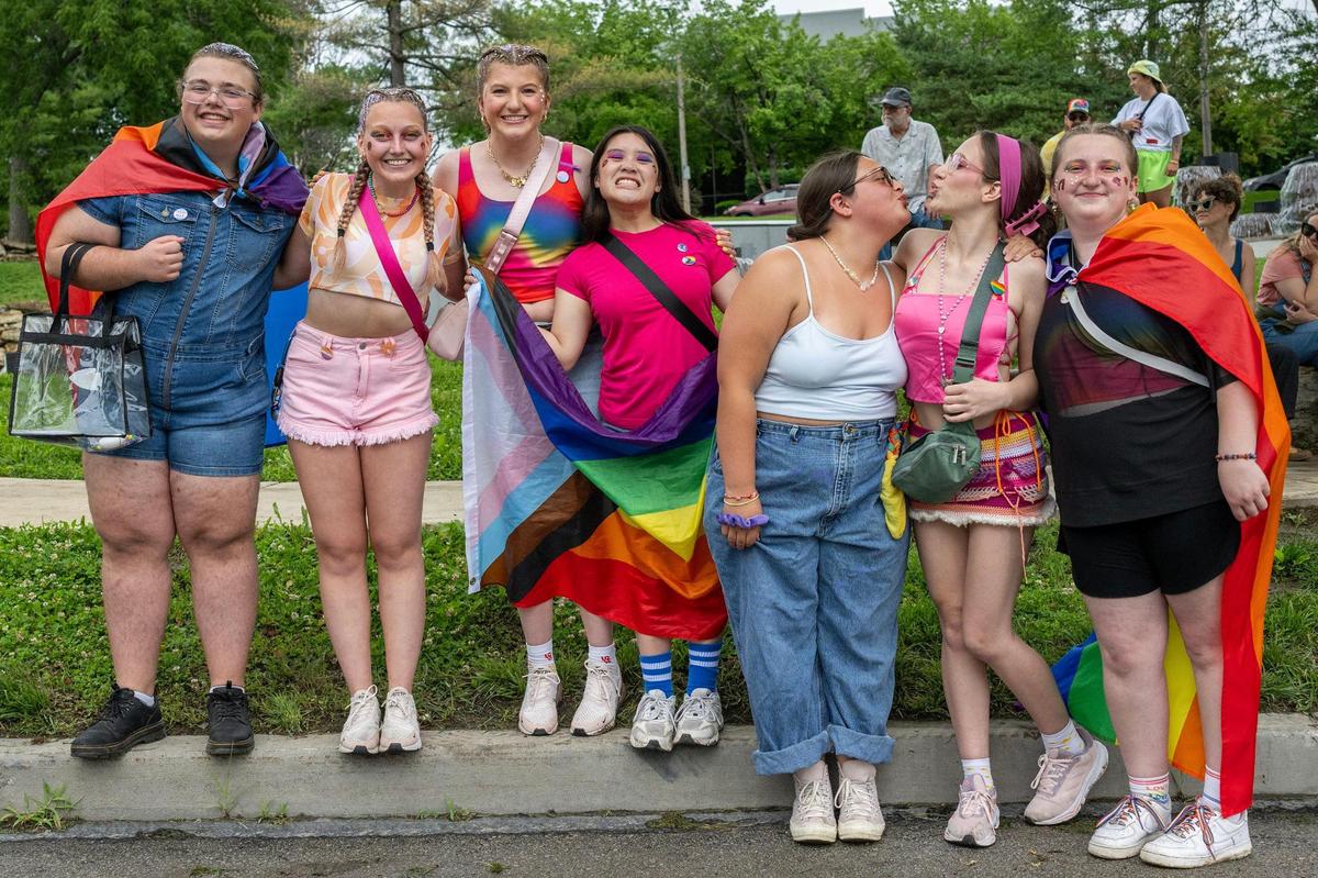 Attendees dressed in Pride-themed attire pose for a photo while watching the KC Pride Parade along Mill Creek Parkway.