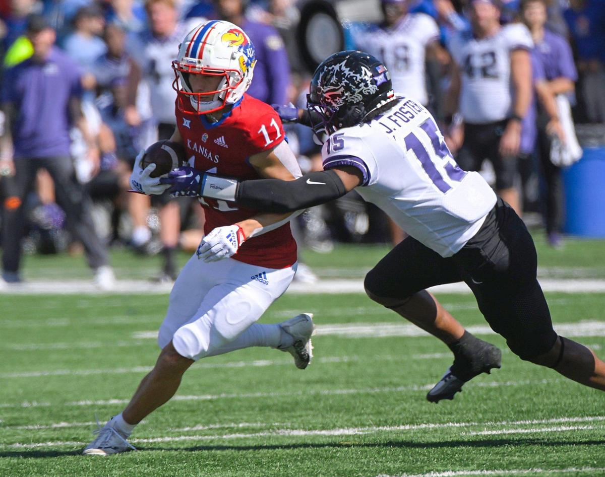 Kansas Jayhawks wide receiver Luke Grimm runs out of the grasp of TCU Horned Frogs safety Josh Foster in the first half Saturday, October 8, 2022, at David Booth Memorial Stadium in Lawrence, Kansas.