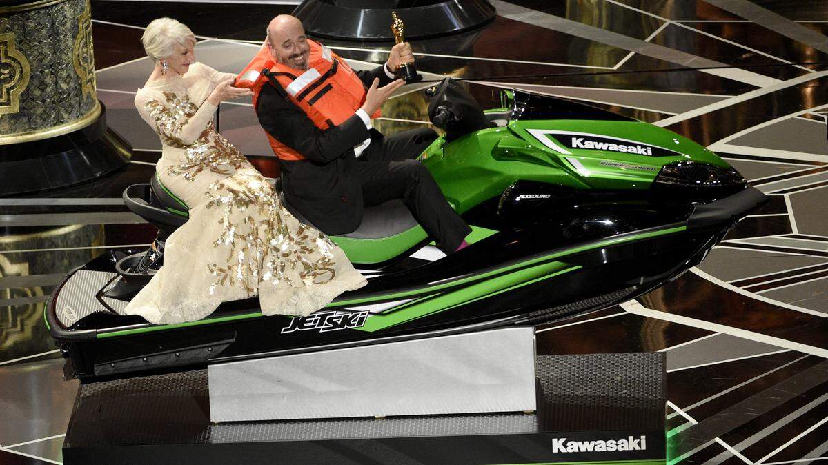 Helen Mirren, left, accompanies Mark Bridges, winner for the award for best costume design for “Phantom Thread,” as he wins a jet ski for having the shortest acceptance speech at the Oscars on Sunday, March 4, 2018, at the Dolby Theatre in Los Angeles.