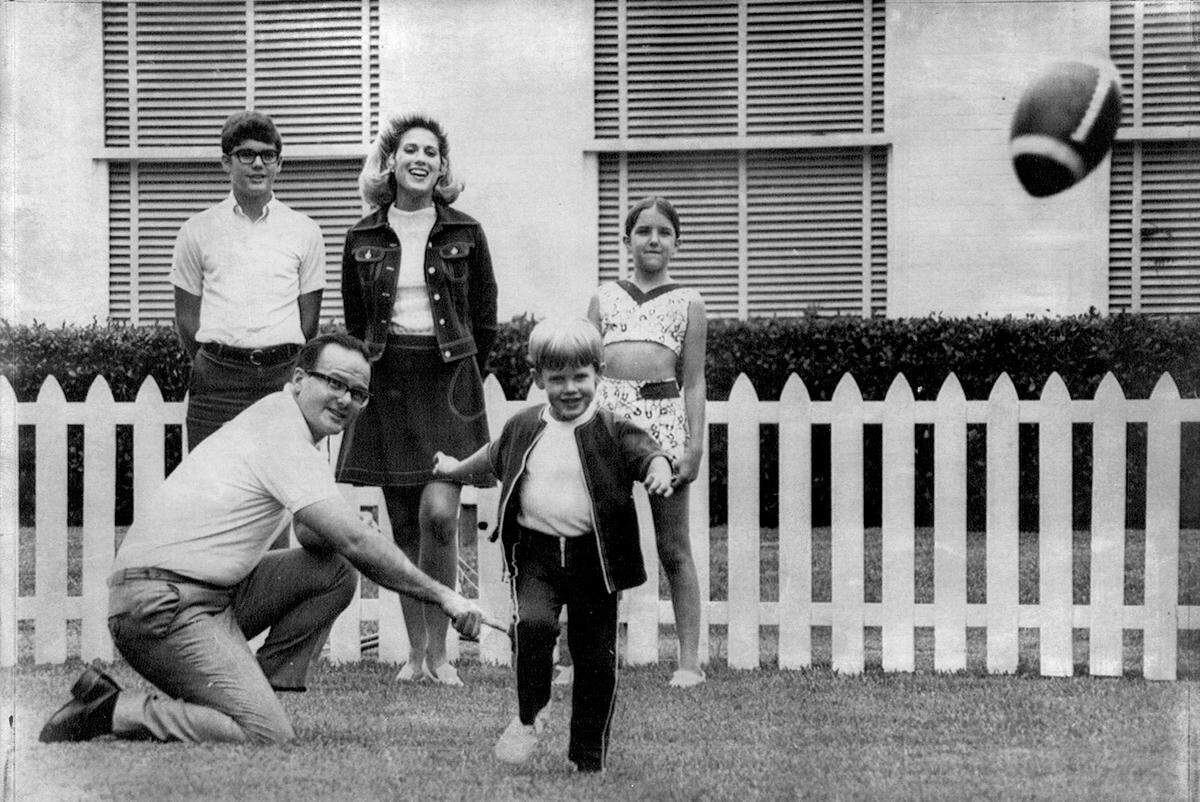 Lamar Hunt holds the football for Clark, his 5-year-old son to kick in this 1970 photo. His wife, Norma, watches along with Lamar, Jr., 13, and Sharon, 12.