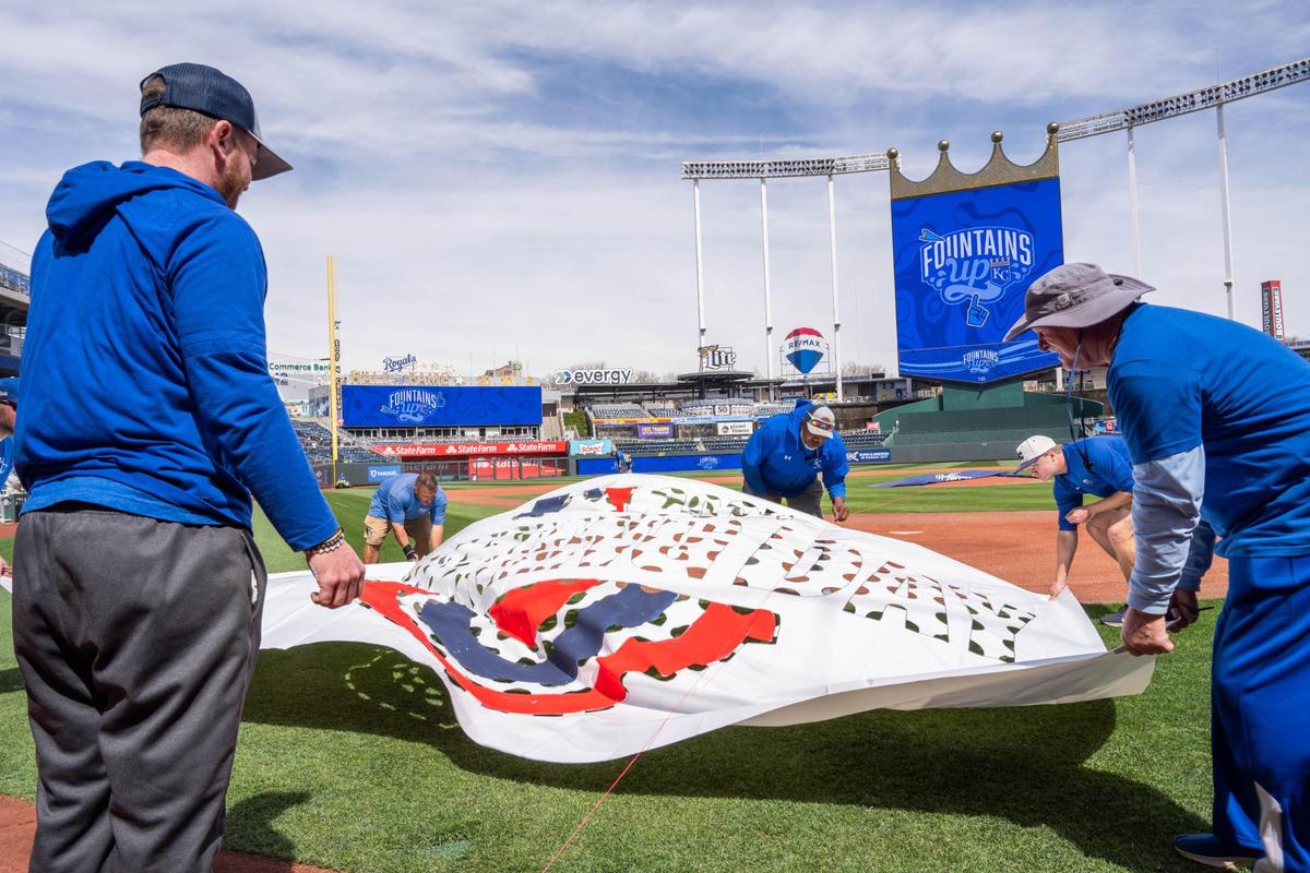 Grounds crew workers lay out a stencil for the MLB Opening Day logo to be painted on the field at Kauffman Stadium on Tuesday, March 25, 2025. Crews worked throughout the day to prepare for Opening Day for the Kansas City Royals.