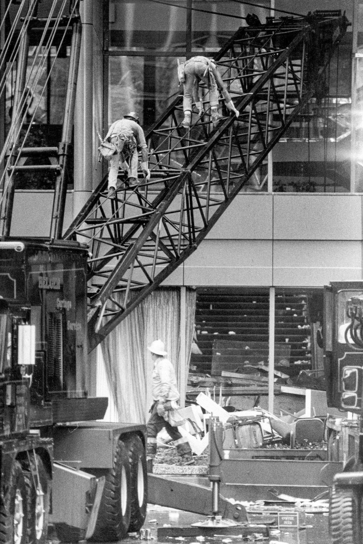 Crane operators climb up the boom of a crane positioned to lift the collapsed skywalks so emergency crews could reach victims trapped under the wreckage.