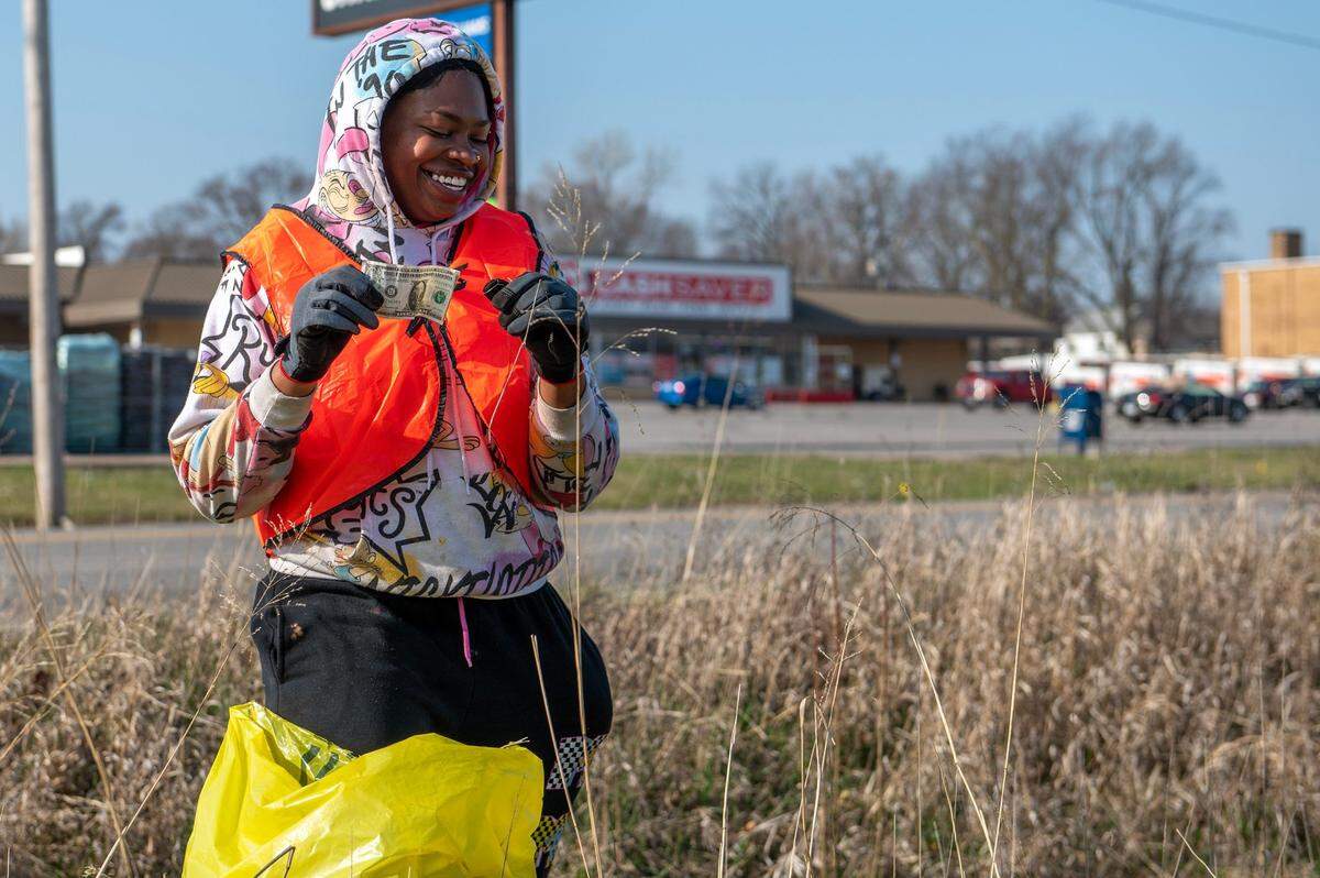 Marquita James, a member of the Community Services League and Independence T.O.G.E.T.H.E.R., finds a dollar while collecting garbage along Independence Ave on March 30 in Independence.