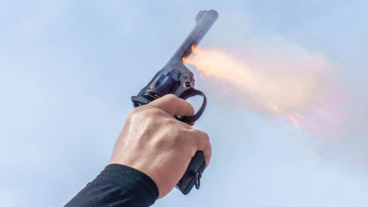 Hand holding pistol firearm pointing up. The pistol is used in sports. celebratory gunfire