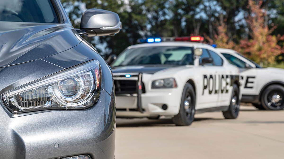 Two police vehicles stop a sedan on a routine traffic stop