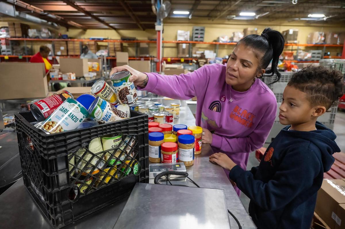 Volunteers Nancy Allen and her son, Maxwell Simmons, 9, of Lee’s Summit, pack protein boxes at Harvesters on the MLK Day of Service on Monday, Jan. 20, 2025, in Kansas City. Harvesters is a community food network that distributes food and resources through more than 900 partner agencies.