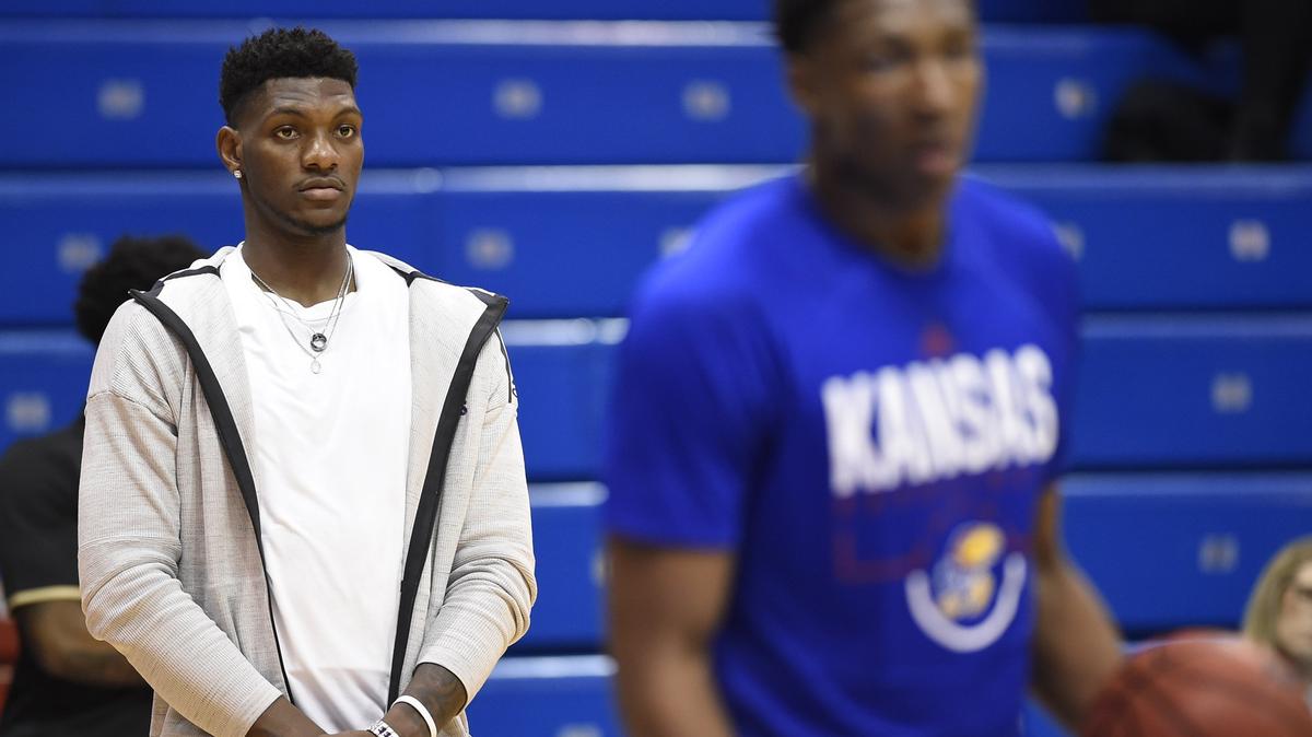 KU’s Silvio DeSousa (left) watched his teammates warmed up before a game last season. His future, whether with KU next season or in the NBA Draft, will be decided soon.