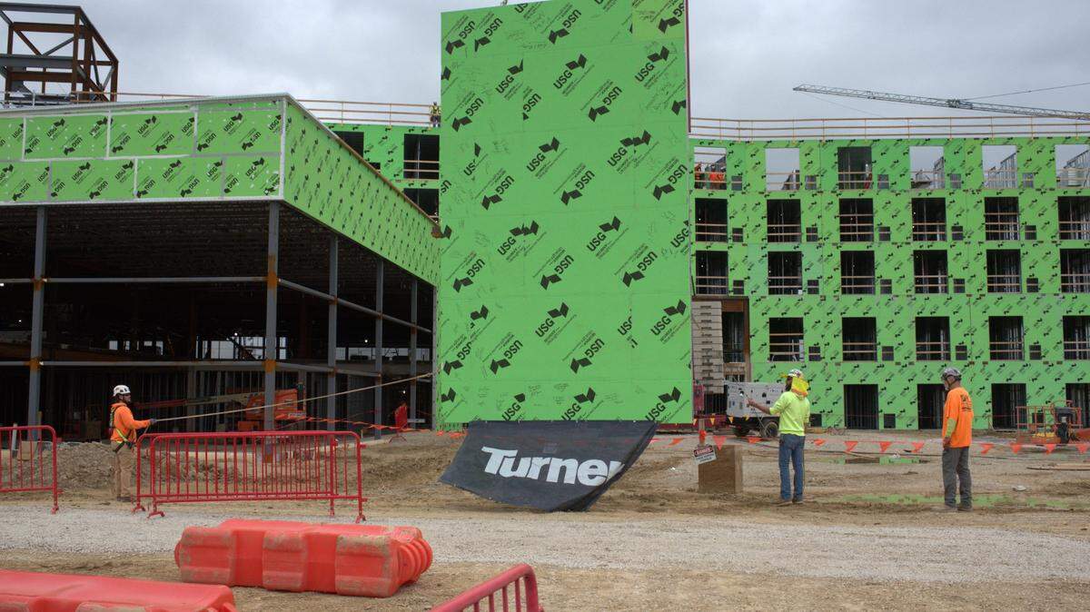 Construction workers prepare to lift a final wall panel by crane during a ceremony on Wednesday, May 8, at the site of the under-construction Margaritaville Hotel in western Kansas City, Kansas.