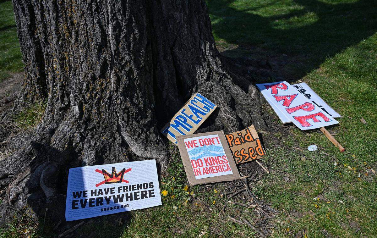 Signs are scattered near a tree in Mill Creek Park on Saturday, March 28, 2026, during a No Kings protest against the Trump administration in Kansas City.