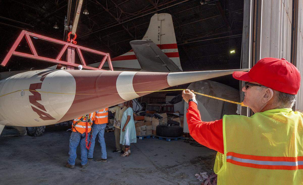 A TWA Museum volunteer takes a final measurement of the TWA Moonliner II before moving it from the Airline History Museum to the TWA Museum on Saturday. The rocket is 32 feet, 5 inches tall.