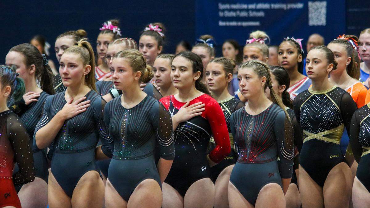 Gymnasts from high schools across Kansas hold their hands to their hearts during the national anthem at the KSHSAA Girls Gymnastics State meet on Oct. 25, 2025 in Olathe.