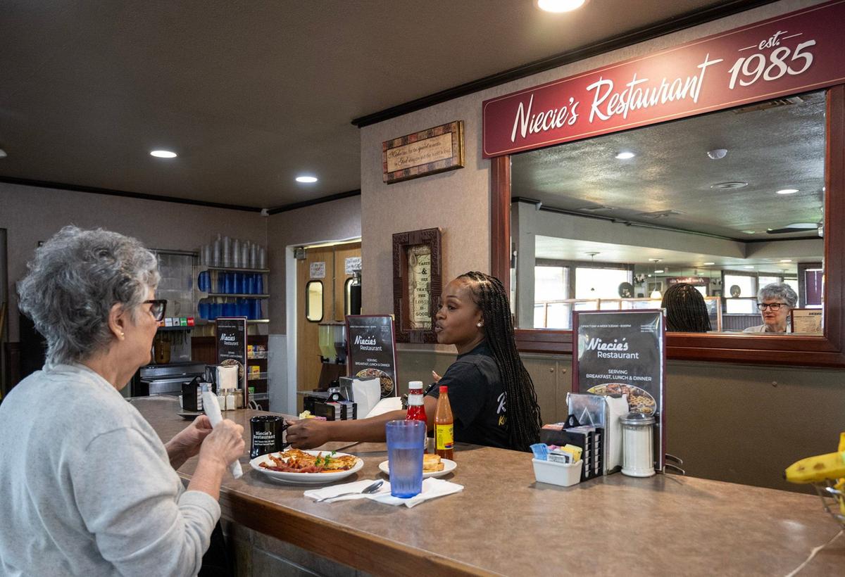 Server Twanee Robinzine refills a coffee for a diner at Niecie’s Restaurant, which, as the sign says, has been around since 1985.