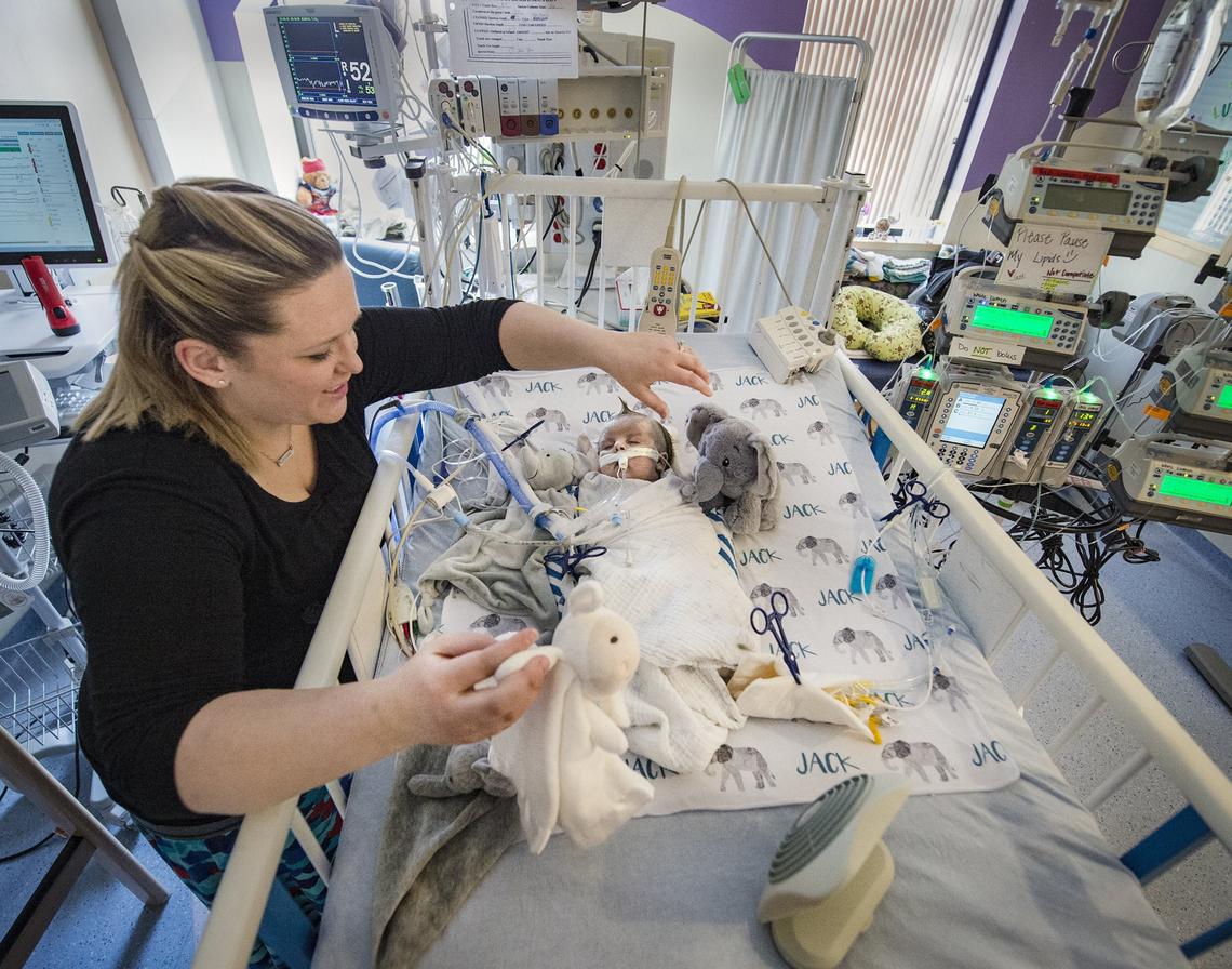 Tiffany Palmer of Kansas City, North, gazes at her son, Jack. The fan at his feet cools the fevers that come with lowering the dosage of morphine and other powerful drugs he's been on.