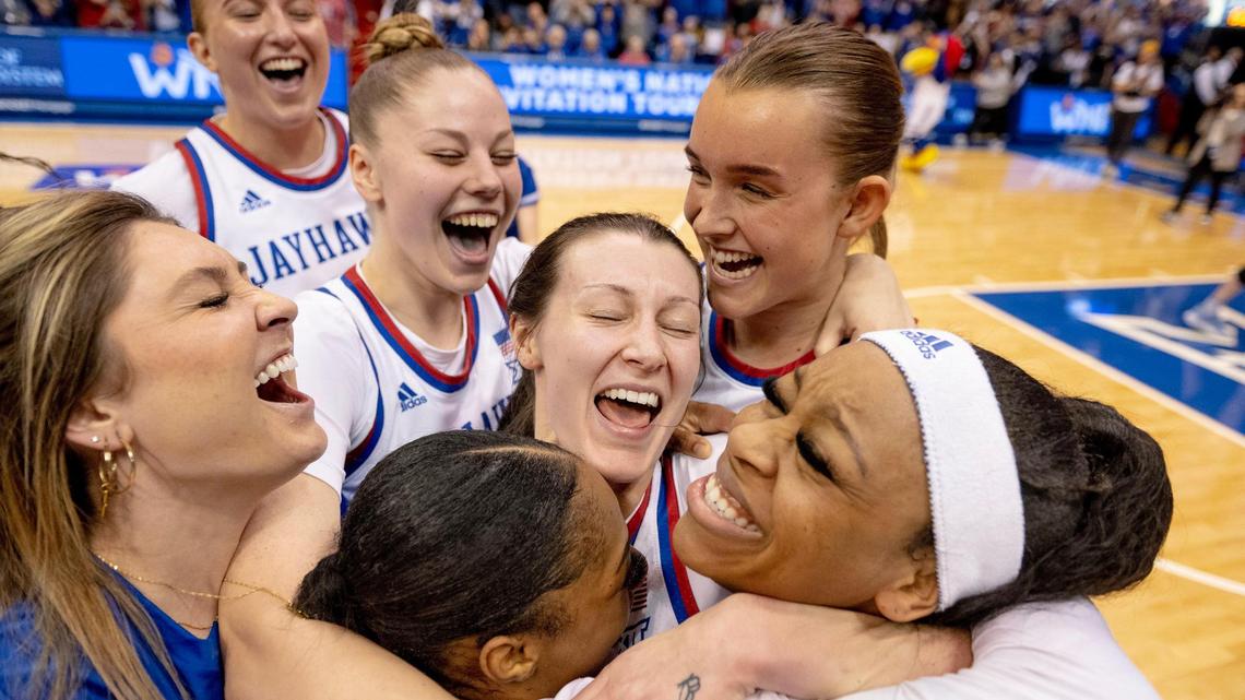 Kansas guard Holly Kersgieter, center, celebrates with guards Wyvette Mayberry, bottom middle, and Chandler Prater, right, after defeating Columbia 66-59 in the finals of the WNIT, Saturday, April 1, 2023, in Lawrence, Kan.