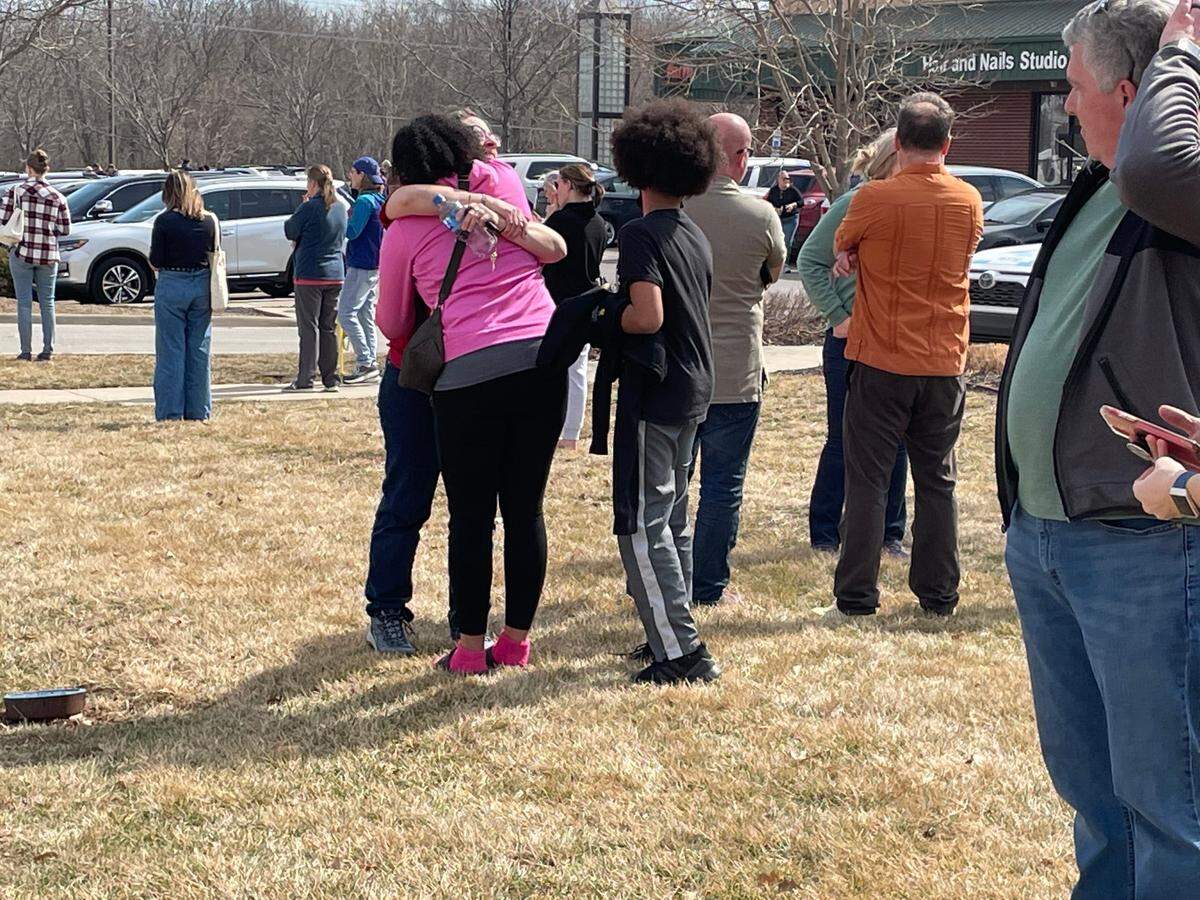 Vesta Morgan, facing camera, hugs another person waiting near Family Video. Morgan hosts an exchange student from Kazakhstan. “There’s a little bit of panic. It’s a child I’m trying to protect. … you know it happens, but you don’t ever think it’s going to be your child or your school.”