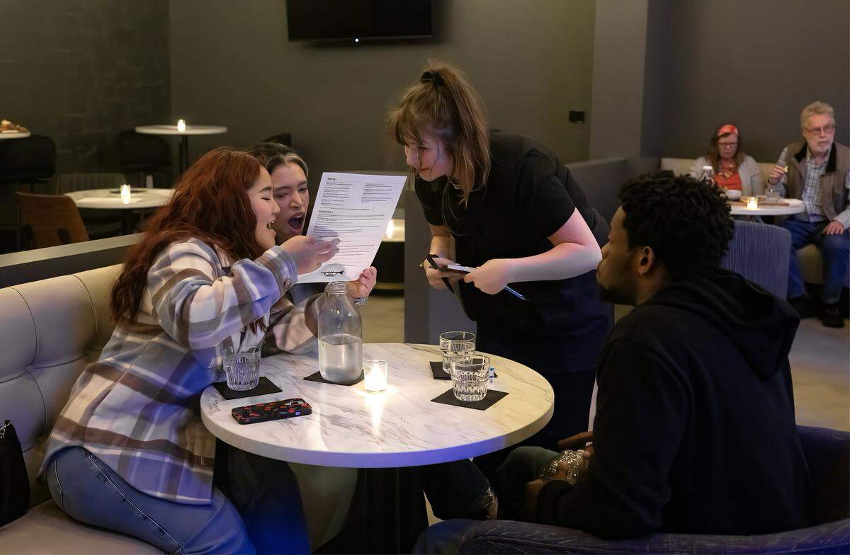 Guests look over the menu and talk with a server at Ted's Taproom on Tuesday, May 5, 2026, in Kansas City. The new jazz venue will feature live music Tuesday through Sunday, at 1829 McGee St. in the Crossroads.
