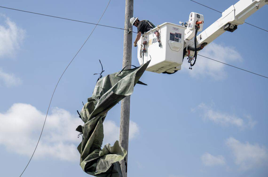 A utility worker from Gardner, Kansas, clears debris from power lines on Tuesday, April 14, 2026, in Ottawa, Kansas. The city of 13,000 was hit by a tornado Monday night, leaving significant damage and power outages across the city.