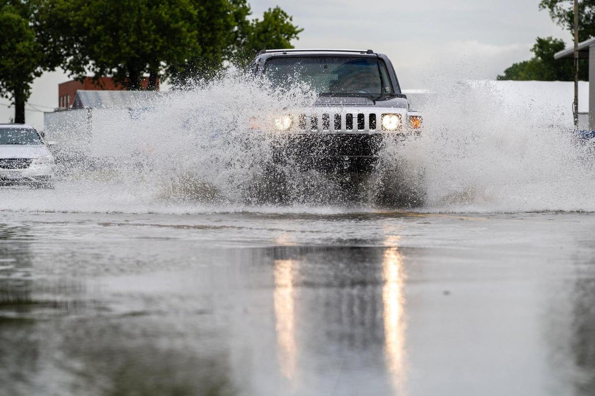 A vehicle drives through floodwaters along Gardner Avenue on Thursday, July 17, 2025, in Kansas City. Flash flooding from heavy overnight rain left portions of the road partially submerged.