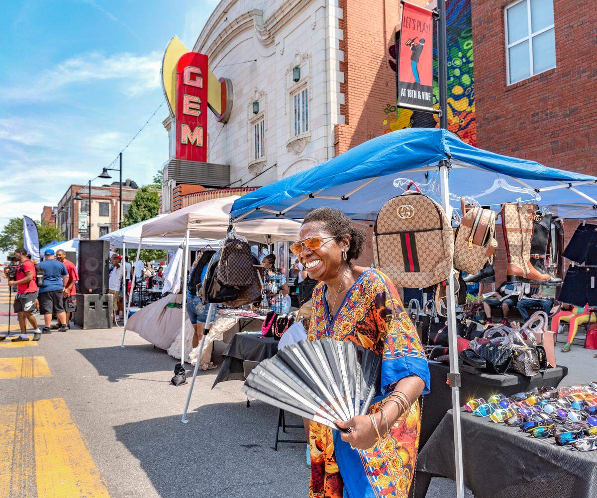 Leslie Shortey, a master life coach, paused to use her fan in the 90-degree heat on Vine Street during 816 Day.