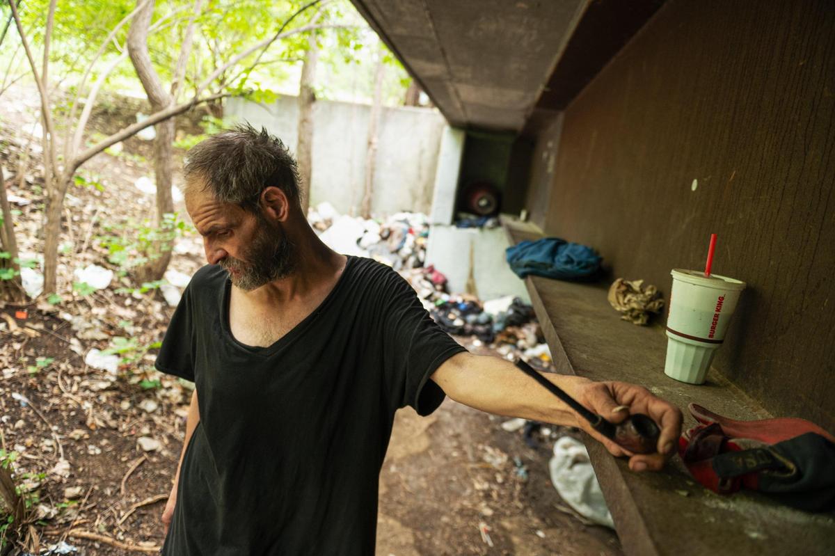 Ken Simard prepares to smoke his tobacco pipe under a bridge where he lives.