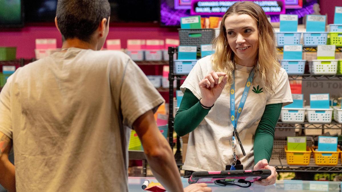 Lily Johnson, a budtender at Fresh Green Dispensary, helps a customer select products on Friday, Feb. 3, 2023, in Kansas City.