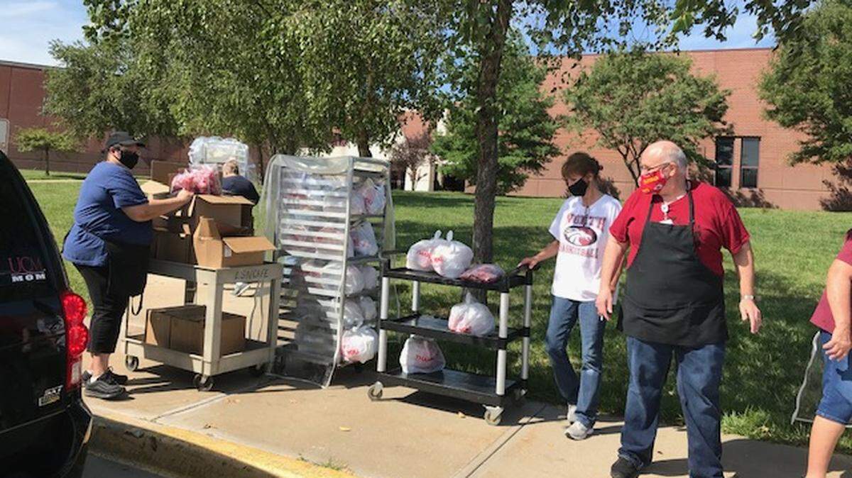 Keith Welhelm, Brandi South and Agga Kupczyk hand out meals curbside at Lee’s Summit North High School.