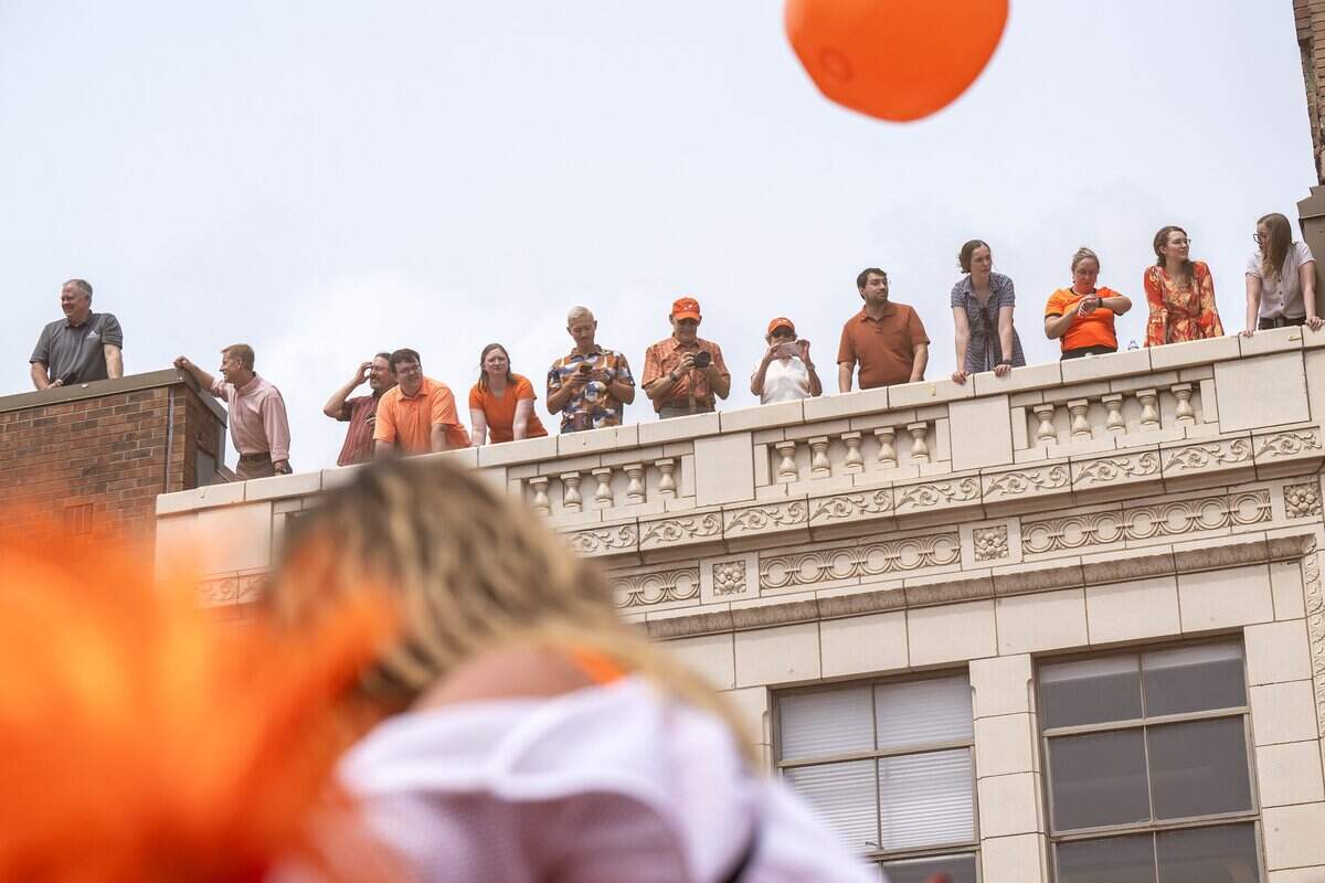Fans watch from a rooftop overlooking Grand Boulevard as participants take part in the Orange Walk on Thursday, June 25, 2026, in Kansas City.