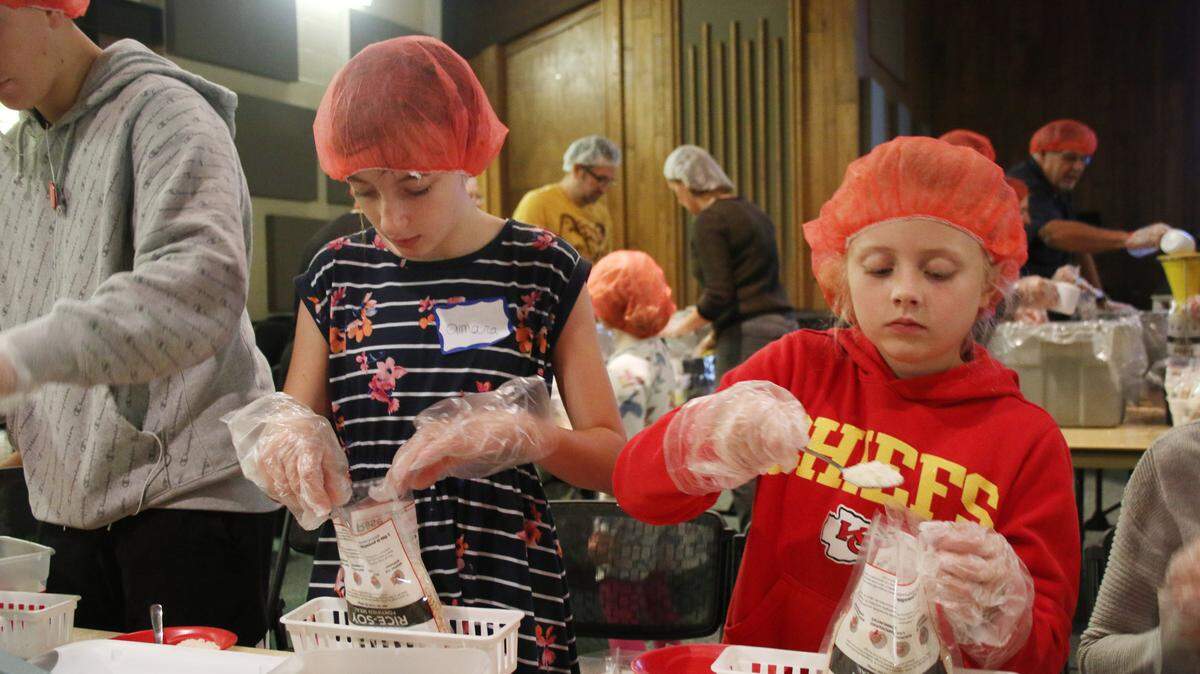 Girl Scouts Amara Wray, 11, and Julia Panter, 10, spoon rice into bags during the Oct. 19 Rise Against Hunger event at First Presbyterian Church.