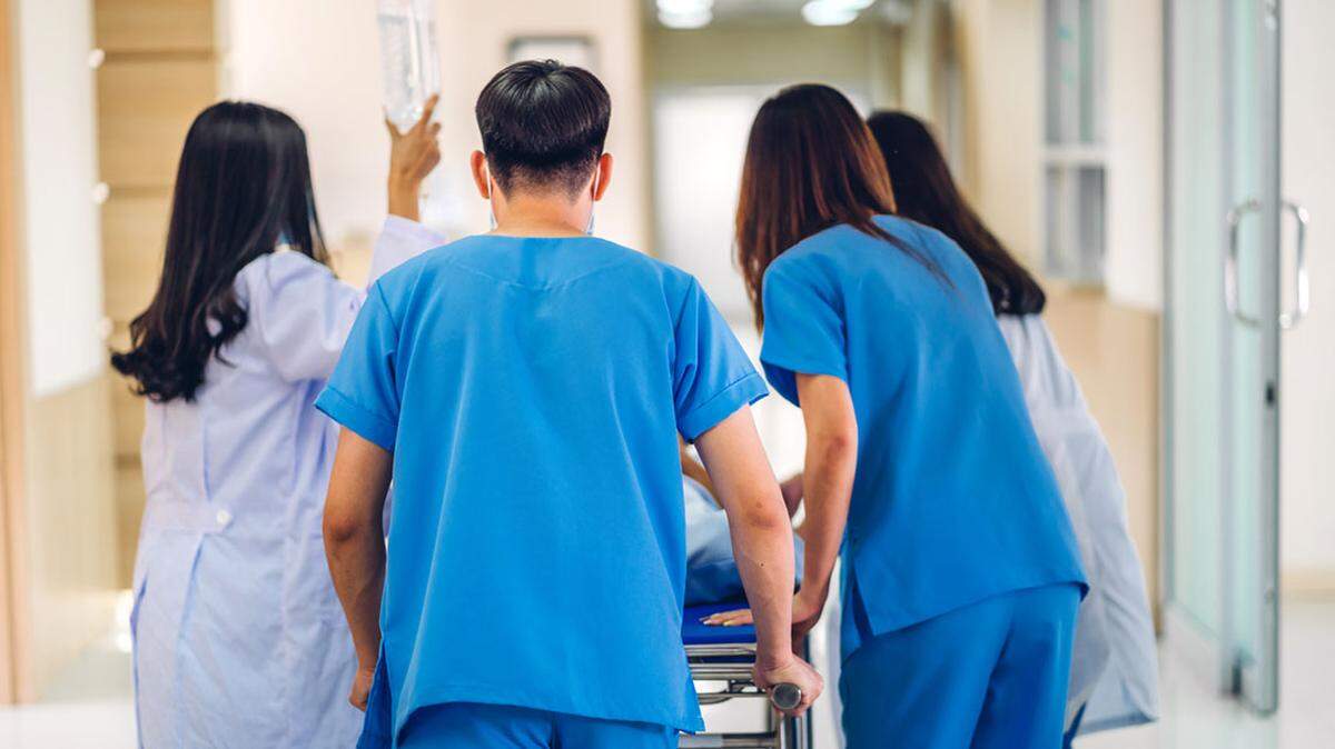 Group of professional medical doctor team and assistant with stethoscope in uniform taking seriously injured patient to operation emergency theatre room in hospital. health medical care concept er emergency room