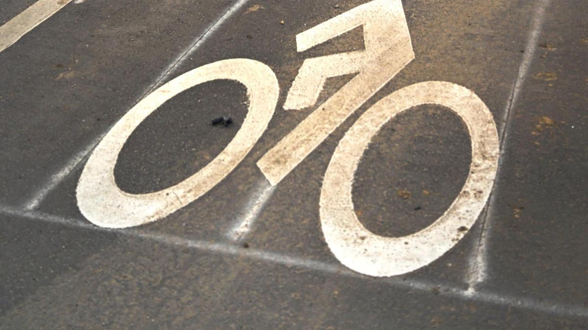 Kia Welch rides a bike in the bike lane on the north side of Truman Road in March 2023 in Kansas City.
