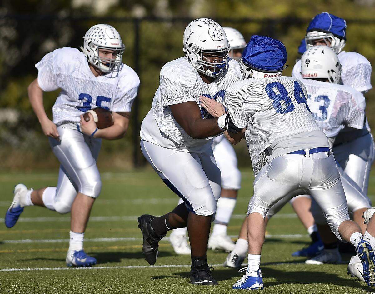 Danielson Ike (center, blocking) practices with his Rockhurst High teammates.